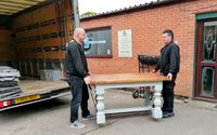 Two men lifting a table into a van